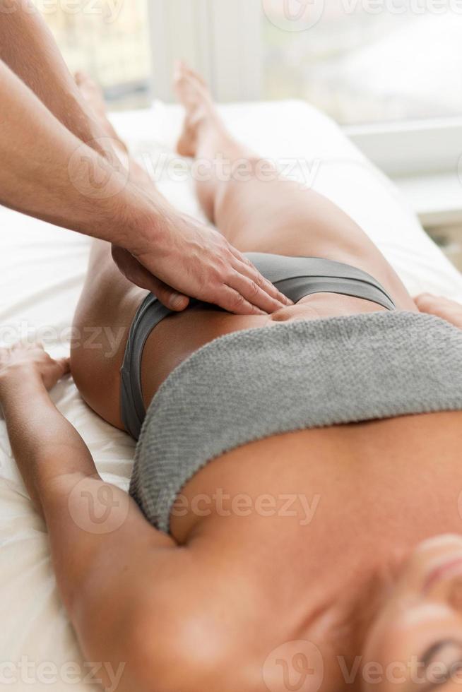 Closeup of masseur man's hands during stomach massage photo