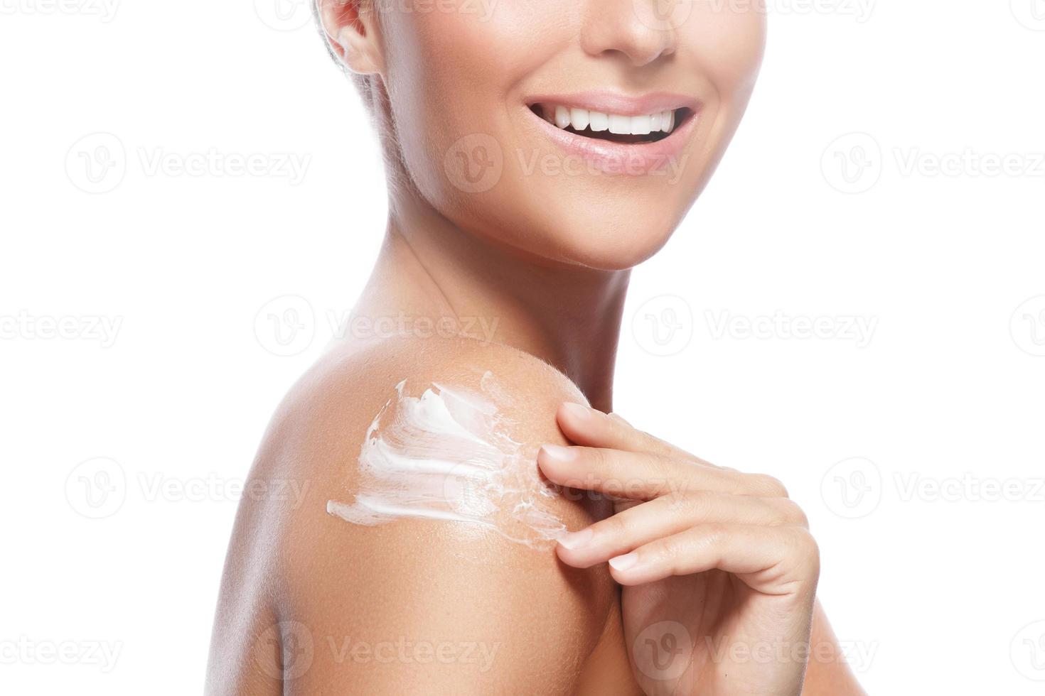 Young and beautiful woman with applying moisturizing cream on her shoulder photo
