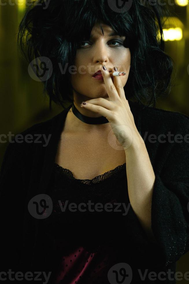 Freaky woman with black hair smoking a cigarette photo