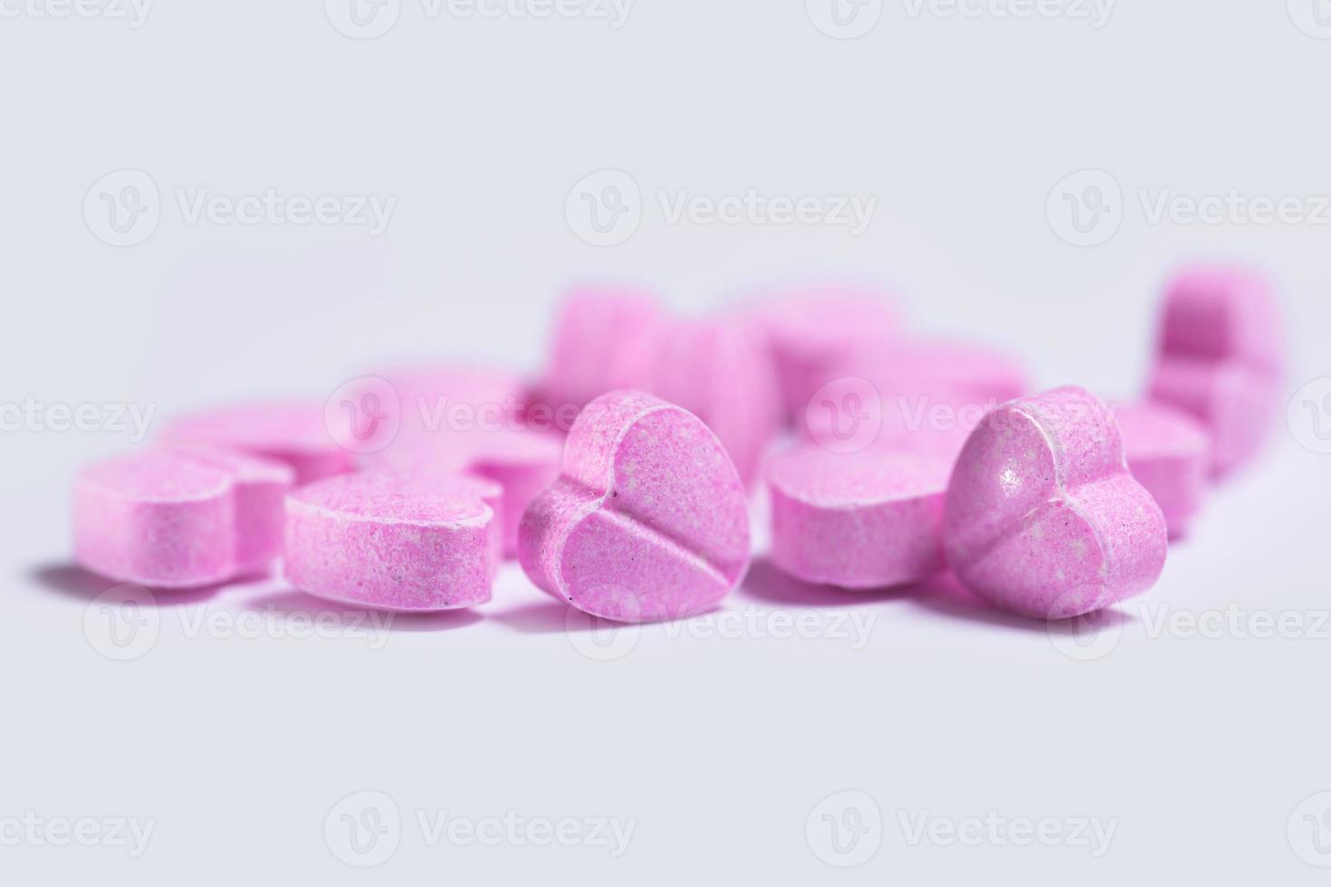 primer plano de pastillas en forma de corazón de color rosa sobre fondo blanco. foto