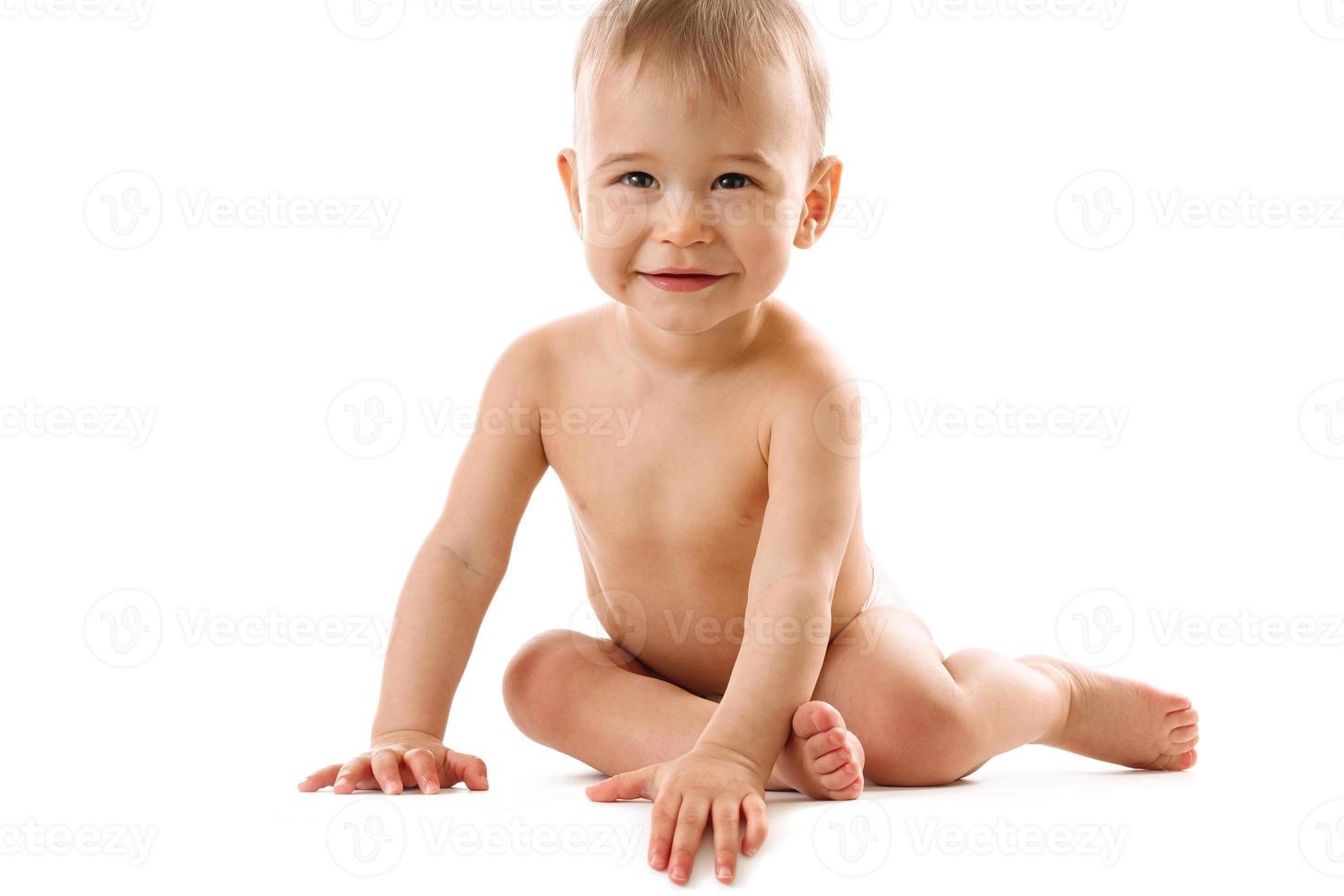 Curious healthy little boy in diaper sitting and smiling. photo