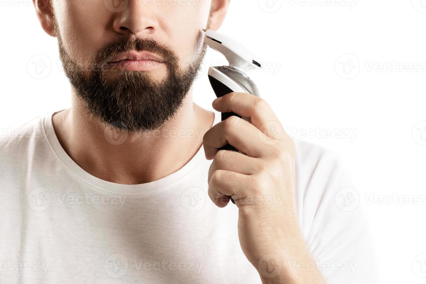 Bearded man is using electric trimmer photo