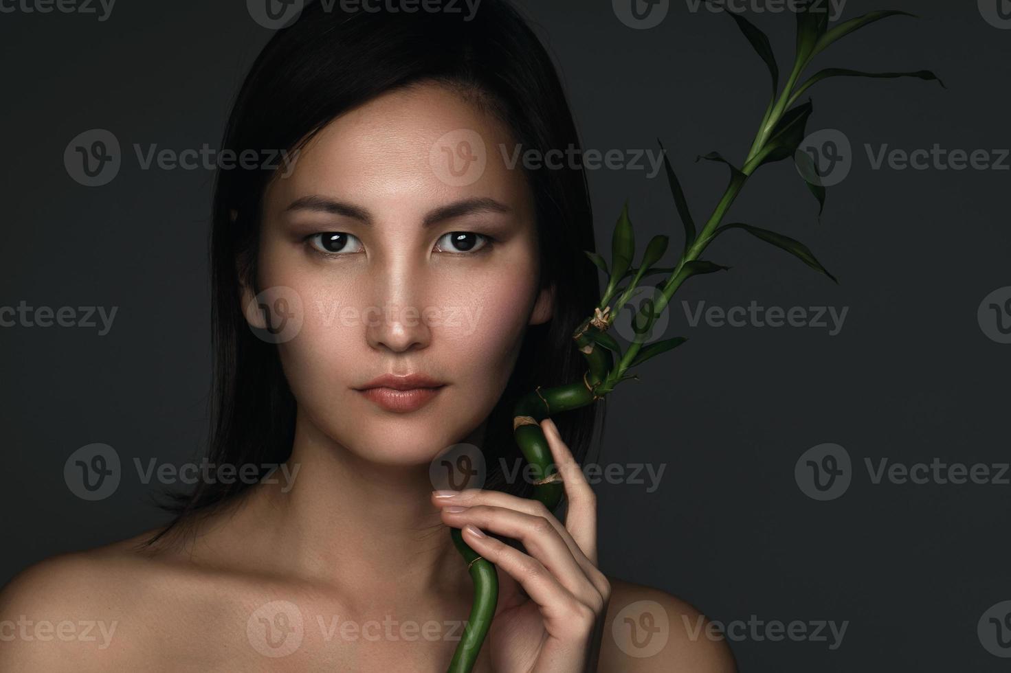 hermosa mujer asiática con una planta de bambú en sus manos foto