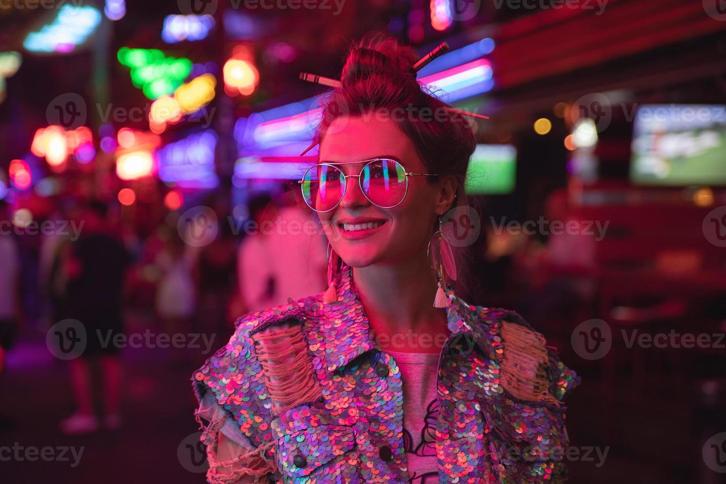 Stylish woman wearing jacket with shining sequins on the city street with neon lights photo