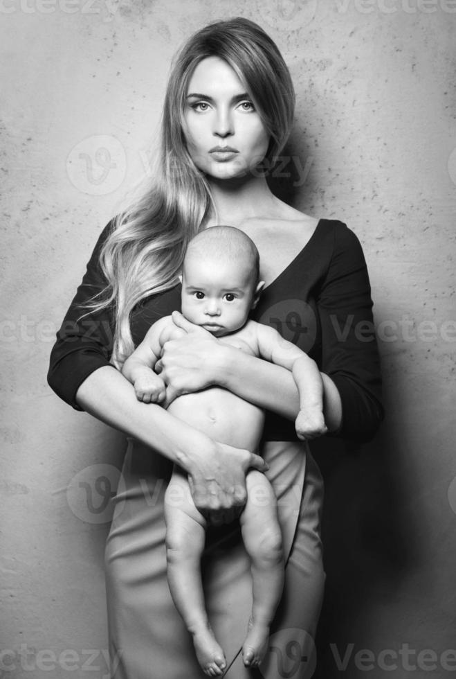 hermosa madre bien vestida con su lindo bebé en sus manos foto