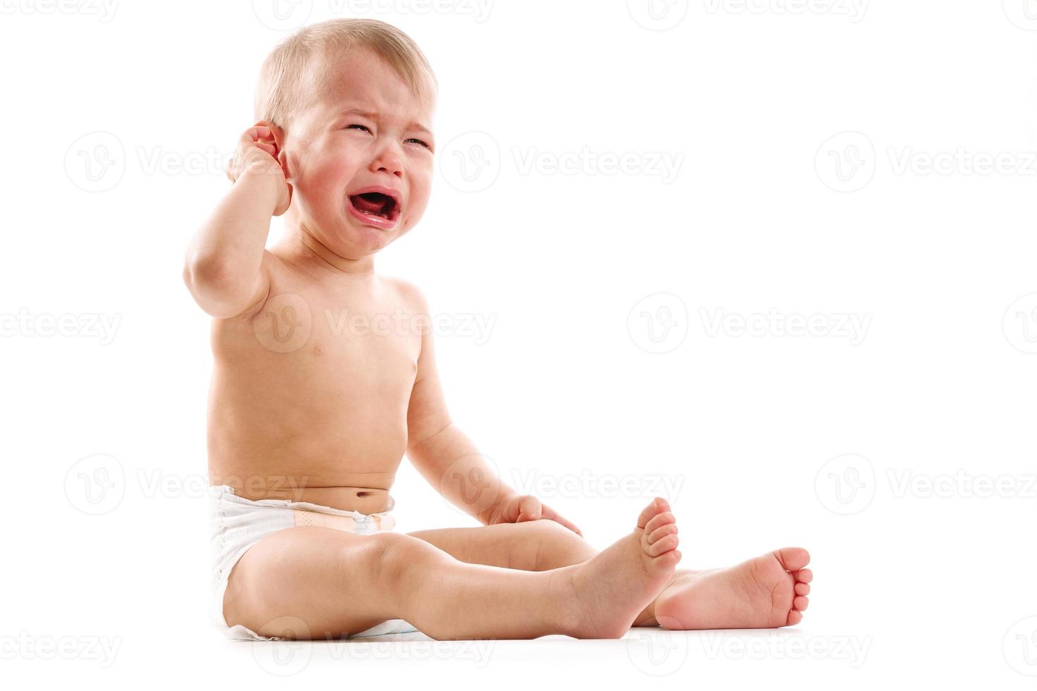 Upset little boy in diaper sitting and crying. photo