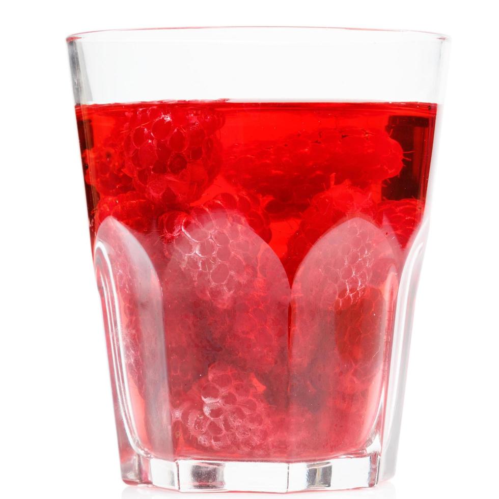 Glass of drink with raspberries on white background photo