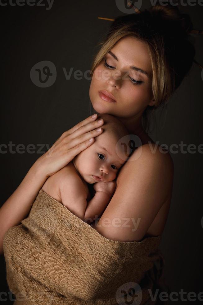 hermosa madre y su pequeño bebé están envueltos en tela de saco foto