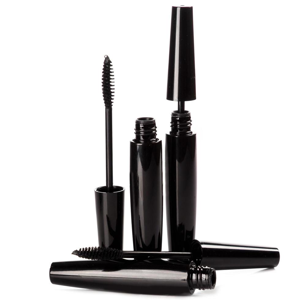 Black mascara brushes and containers on white background photo