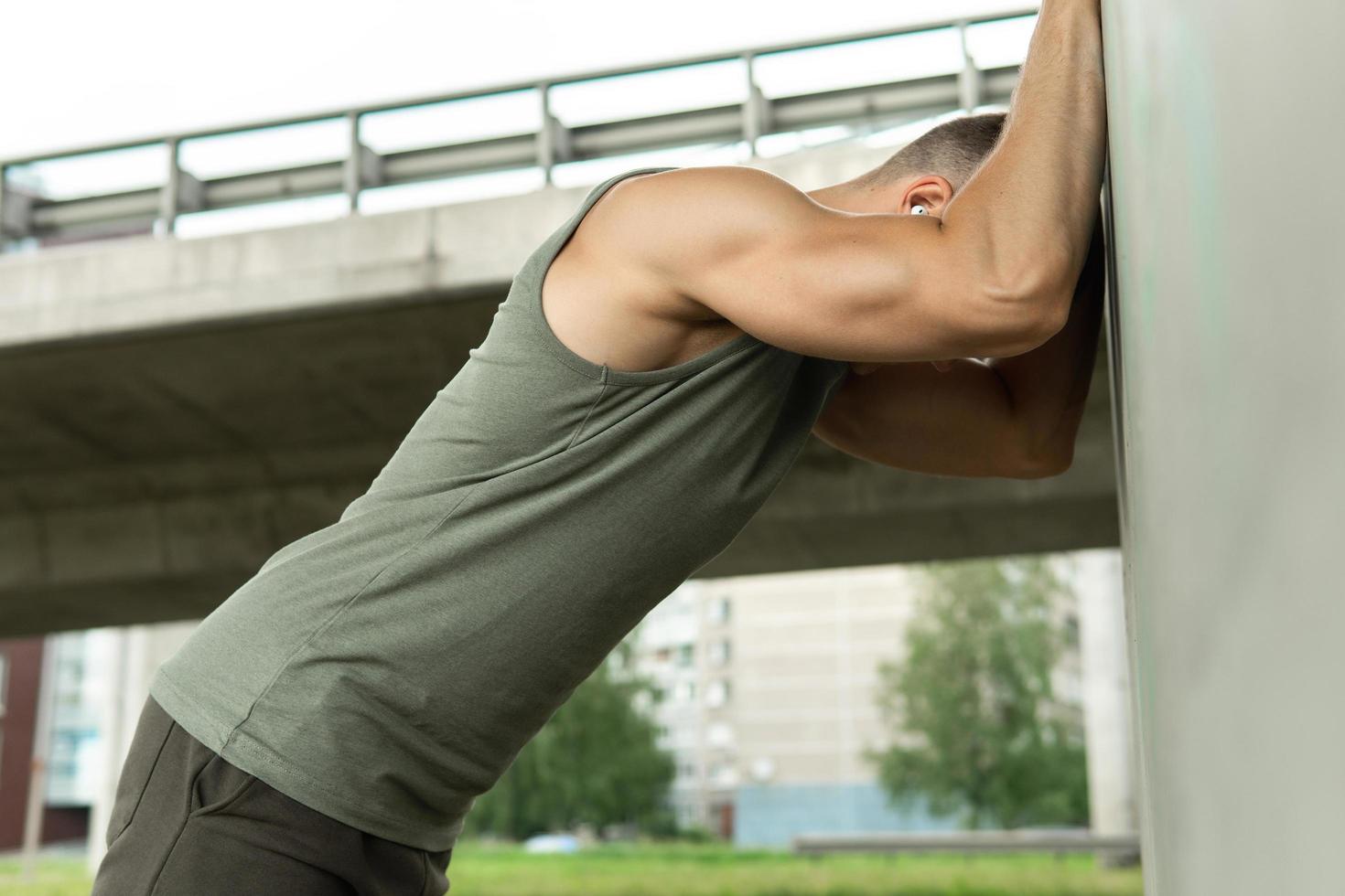 Muscular man warming up before his outdoor fitness workout photo