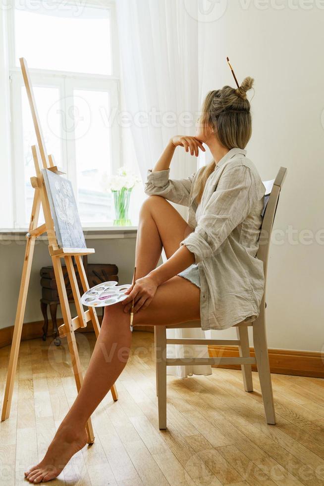 Young woman artist painting on canvas on the easel photo