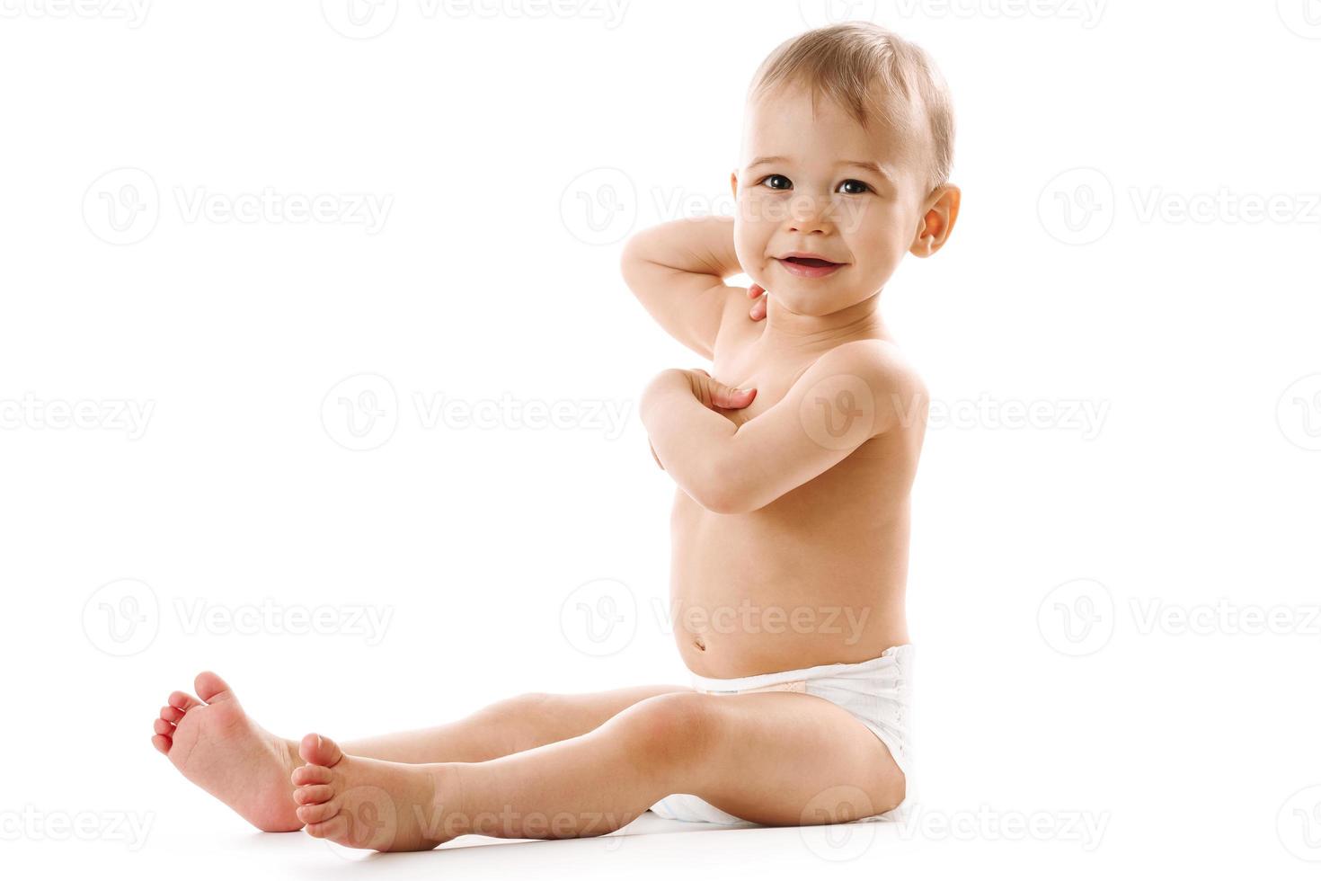 Curious healthy little boy in diaper sitting and smiling. photo