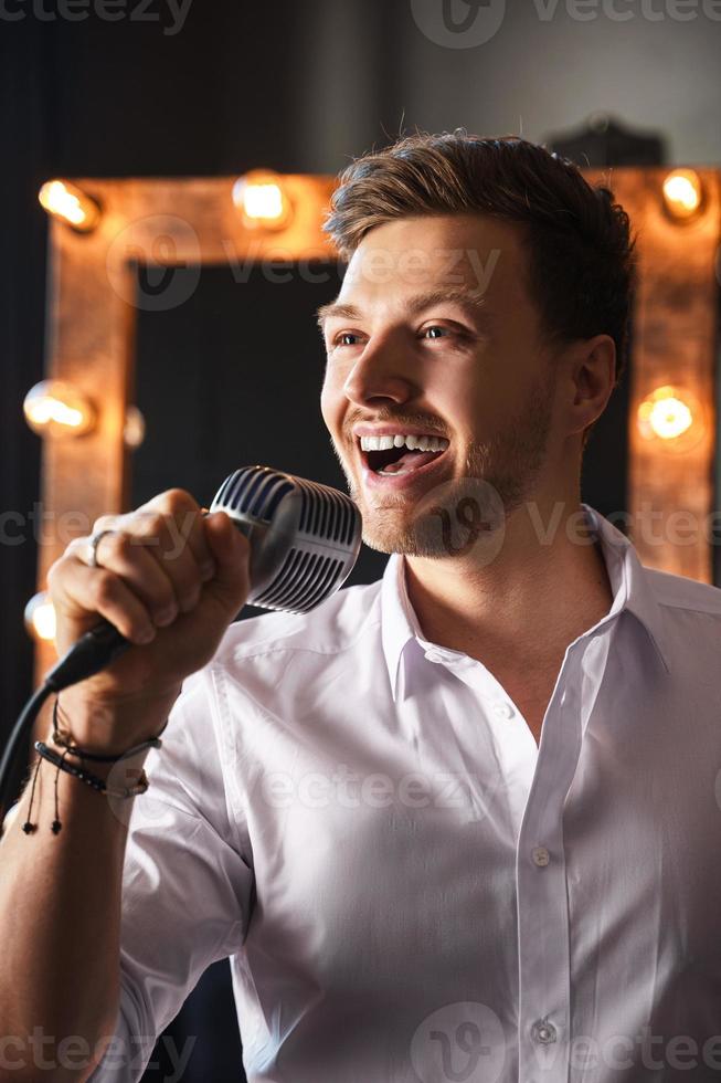 Young man with microphone is singing at home photo