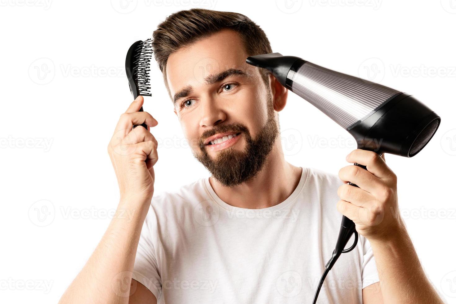 Handsome man is using hair brush and hairdryer for his hairstyle photo