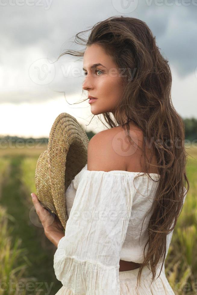 Young lovely woman holding straw hat in the rice field photo