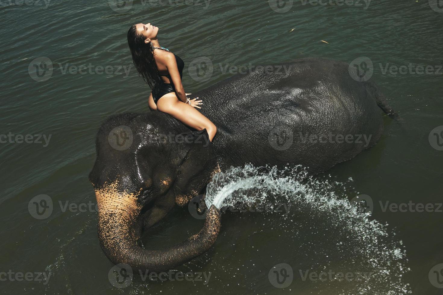 mujer feliz se está bañando con el elefante en el río foto