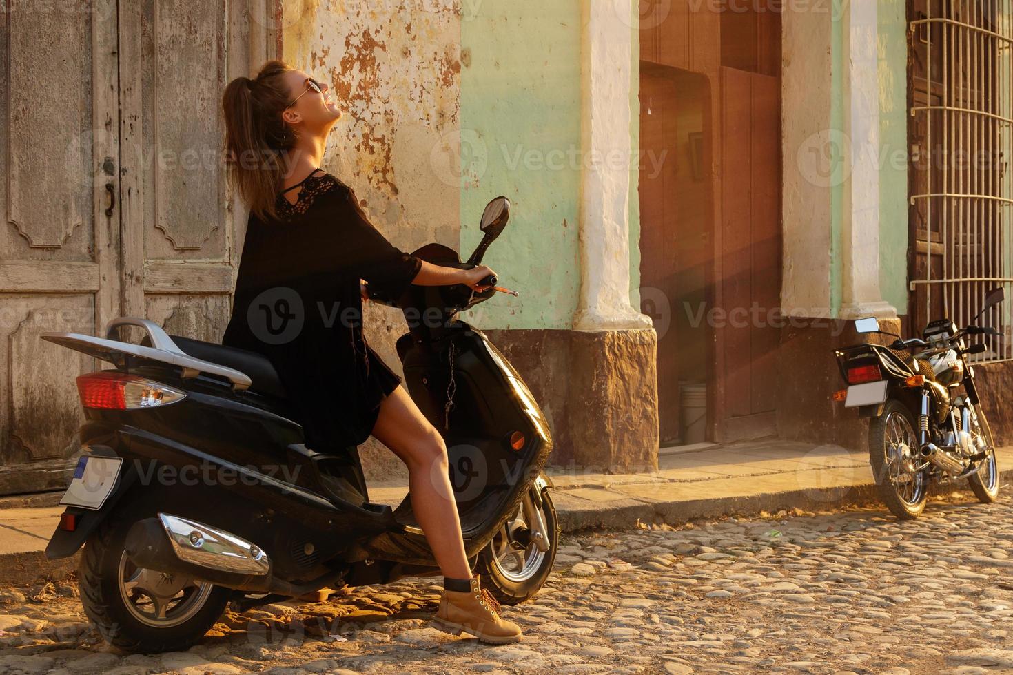Woman traveler driving scooter by the old city streets photo