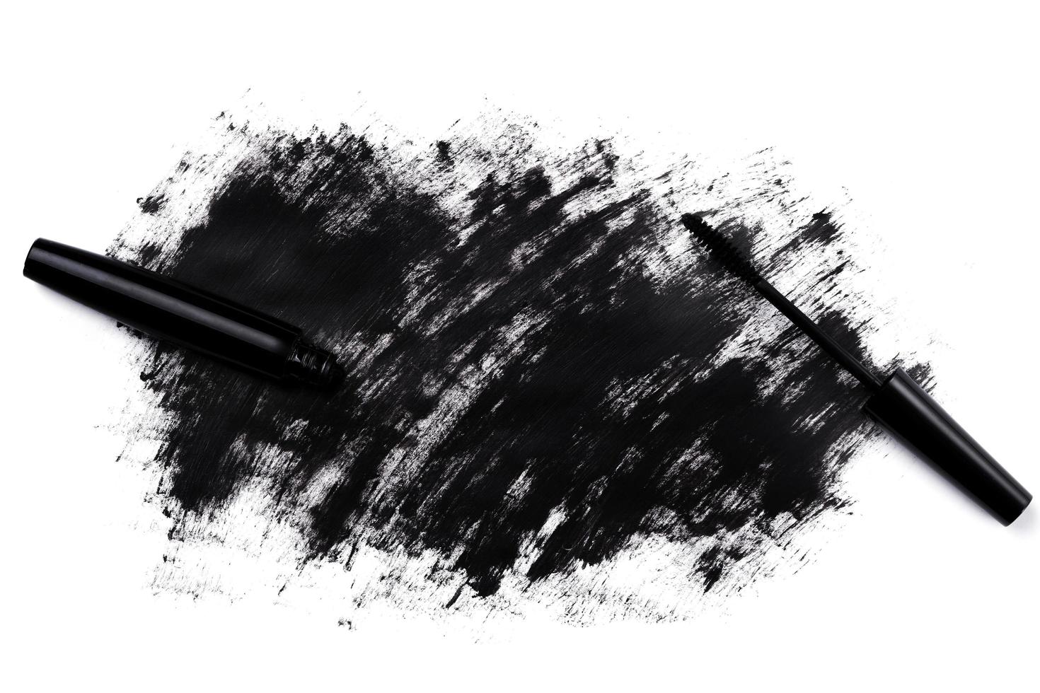 Black wand and smudged mascara on white background photo