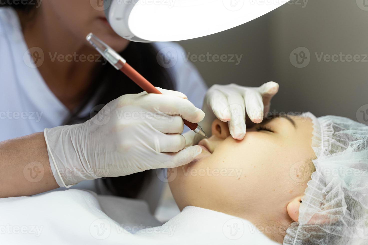 Permanent makeup artist and her client during lip blushing procedure photo
