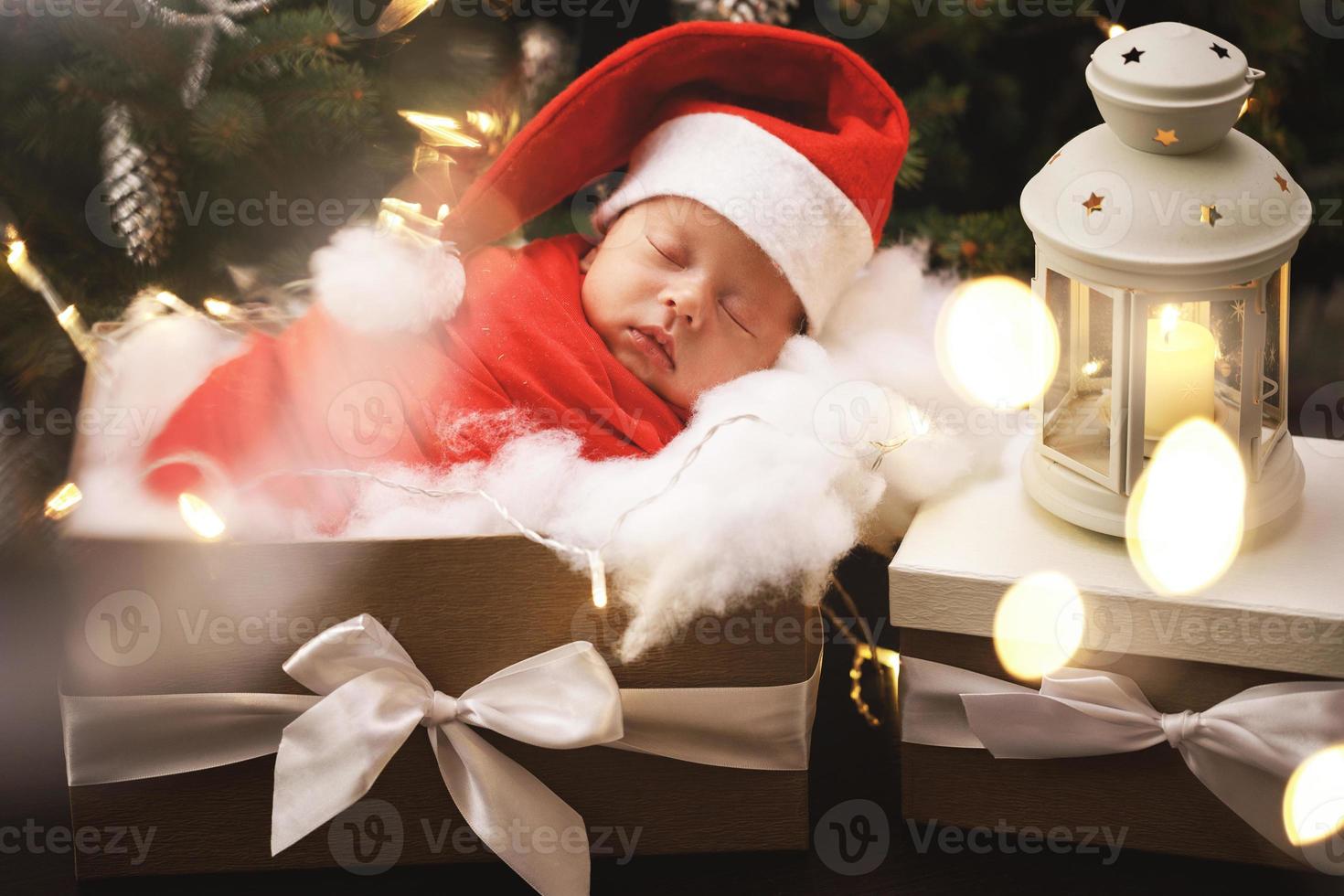 lindo bebé recién nacido con sombrero de santa claus está durmiendo en la caja de regalo de navidad foto