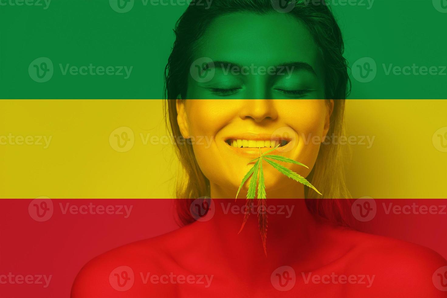 hermosa mujer con una hoja de cannabis en colores de la bandera rastafari foto