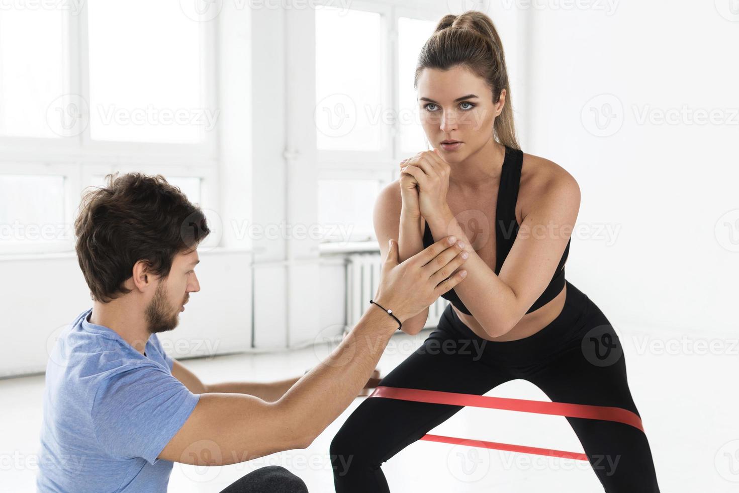 Young woman during workout with a personal fitness instructor in the gym photo