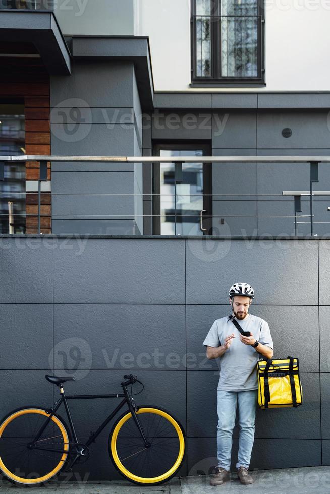 mensajero de entrega de alimentos exprés con bolsa aislada mirando el teléfono. foto
