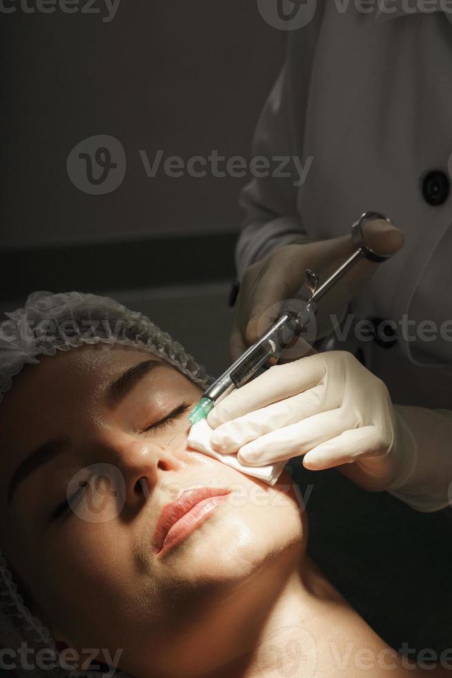 Woman getting injection of local anesthetic before mole removal treatment in a medical aesthetic clinic photo