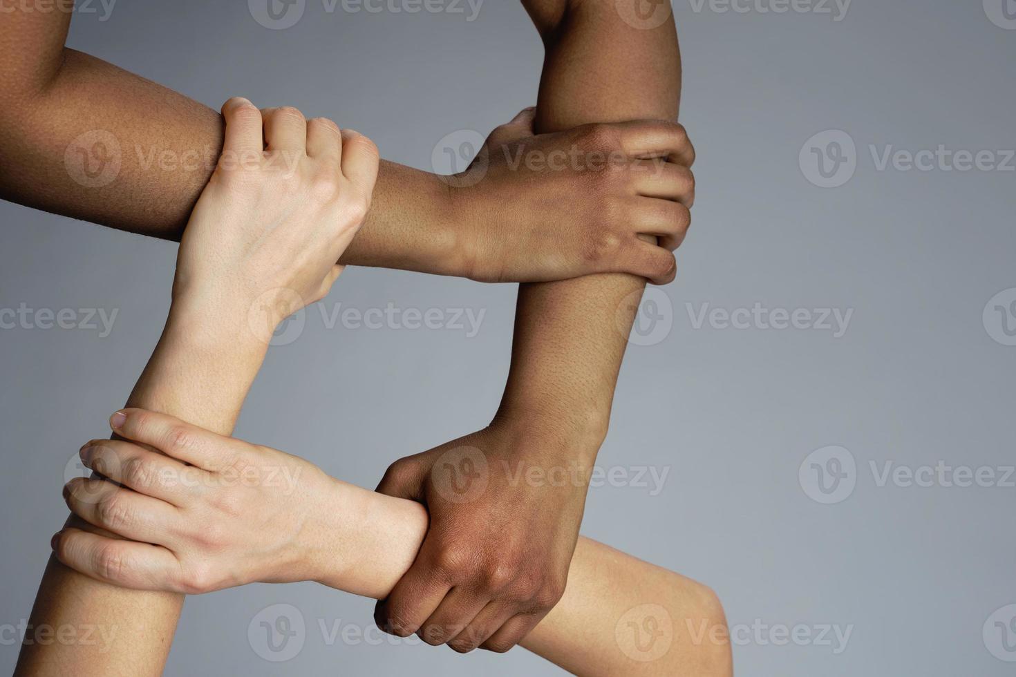 African and Caucasian female hands on gray background photo