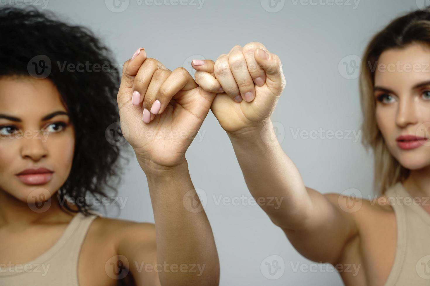 A pinky promise gesture between African and Caucasian women. photo