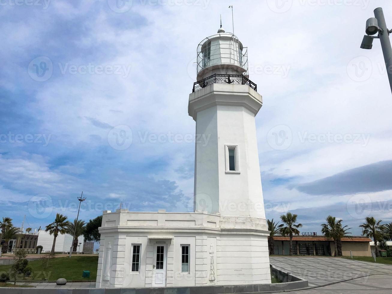 gran faro blanco de piedra alta en el mar tropical cálido resort de verano con palmeras contra el cielo azul foto