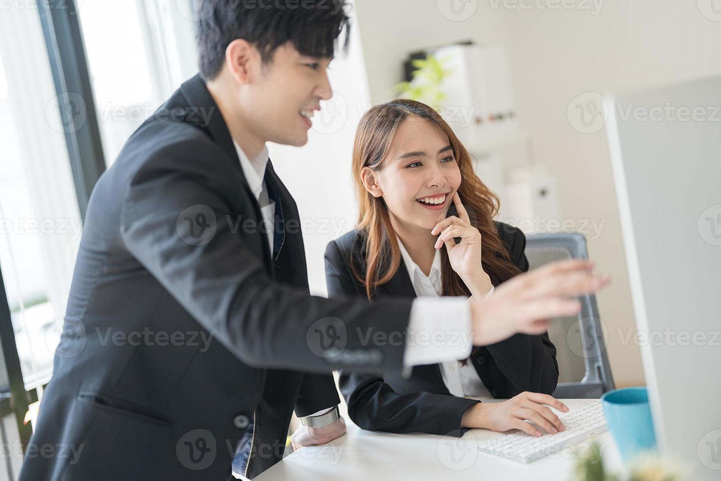 Business people sitting together at a desk using laptops in the office photo