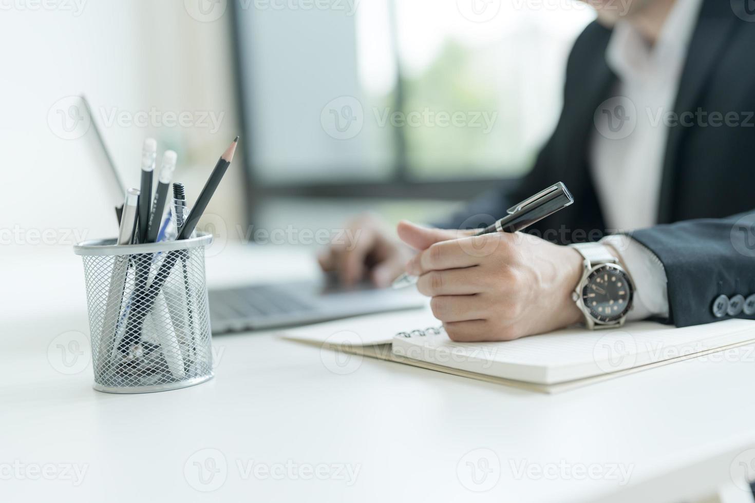 Young businessman opening a notebook View emails from customers sent. and write down the details. photo