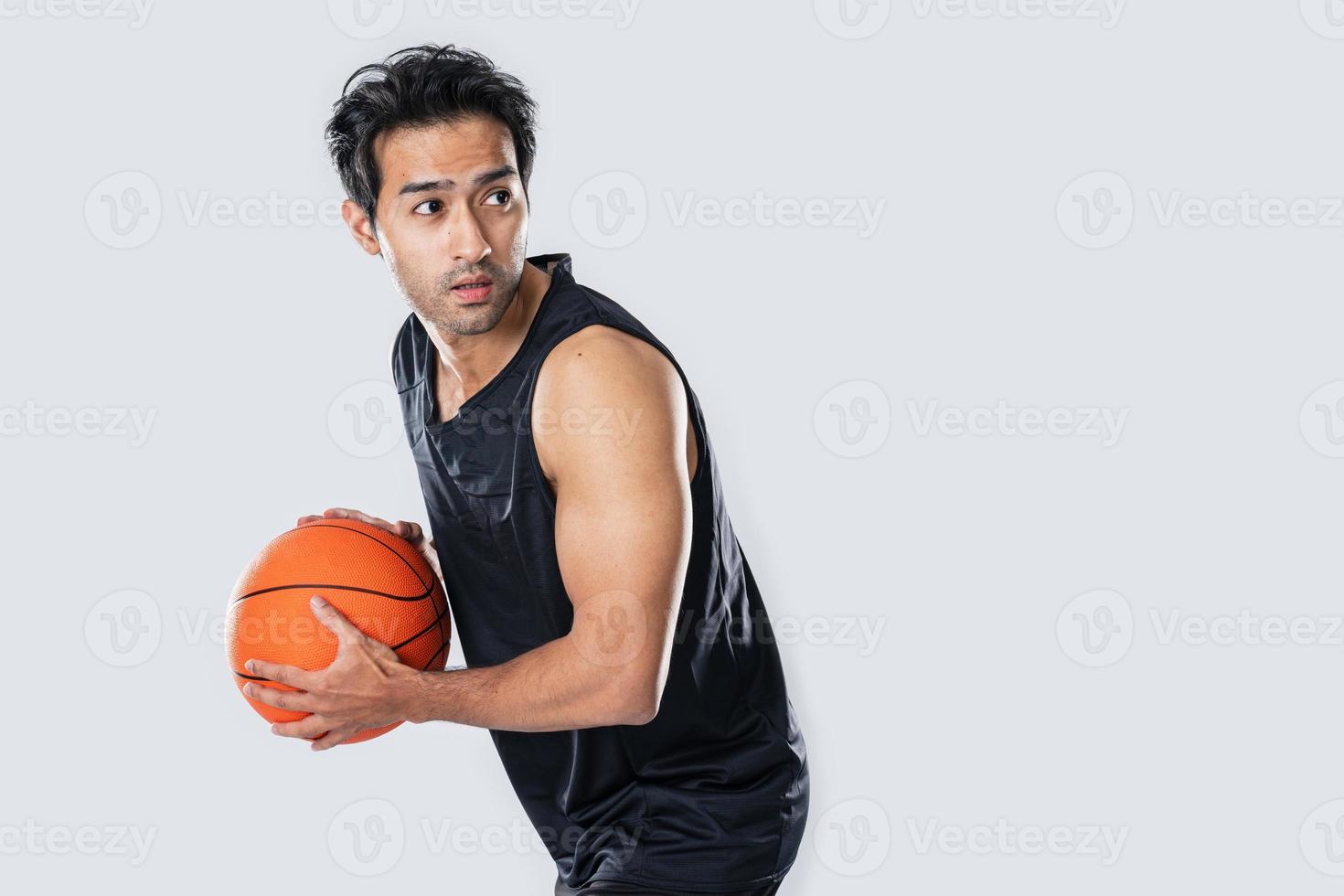 Male basketball player wearing sportswear holding basketball on white background. photo