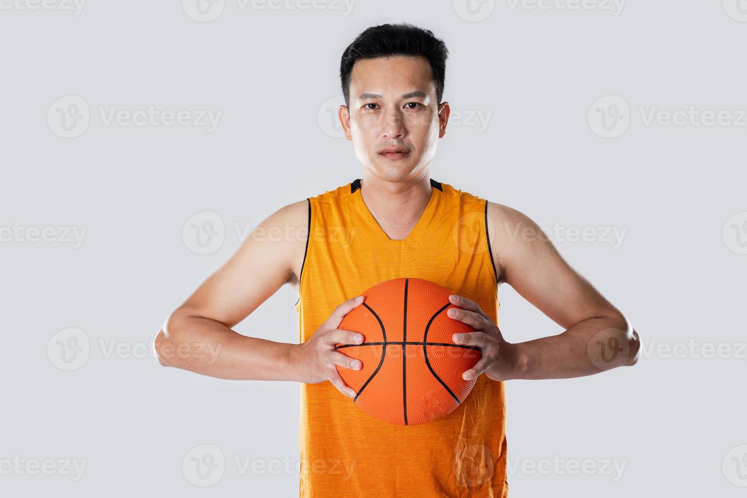 Male basketball player wearing sportswear holding basketball on white background. photo