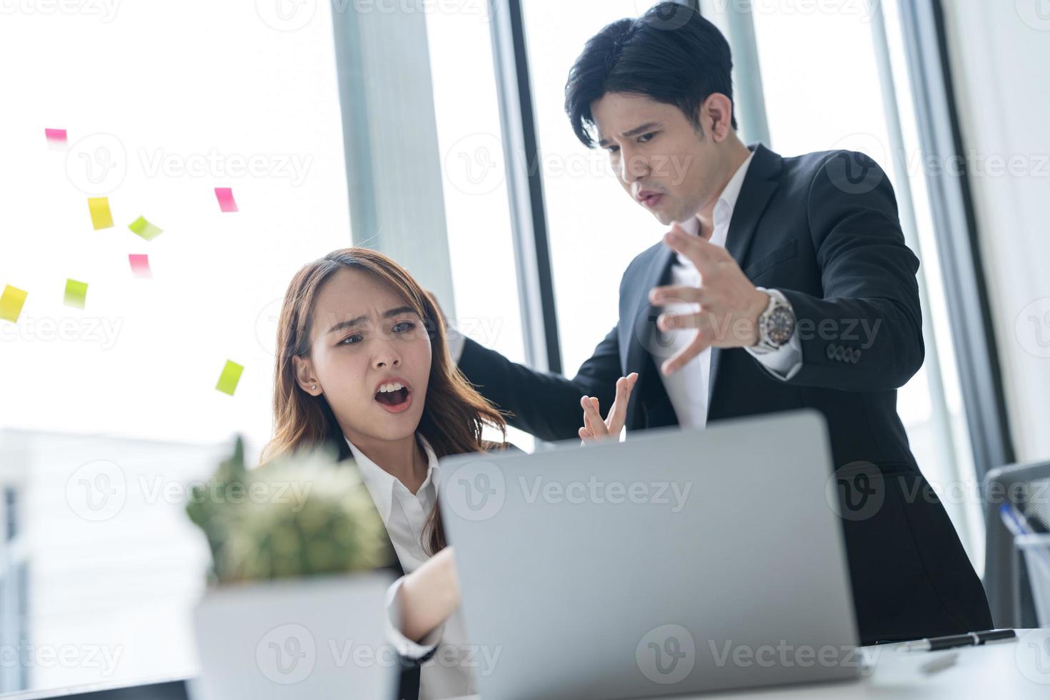 Business people sitting together at a desk using laptops in the office The two of them had a serious, worried expression on their faces while working together photo
