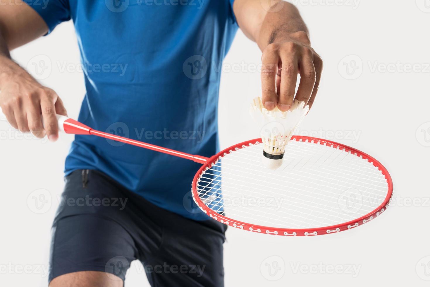 A badminton player in sportswear stands holding a racket and shuttlecock. photo