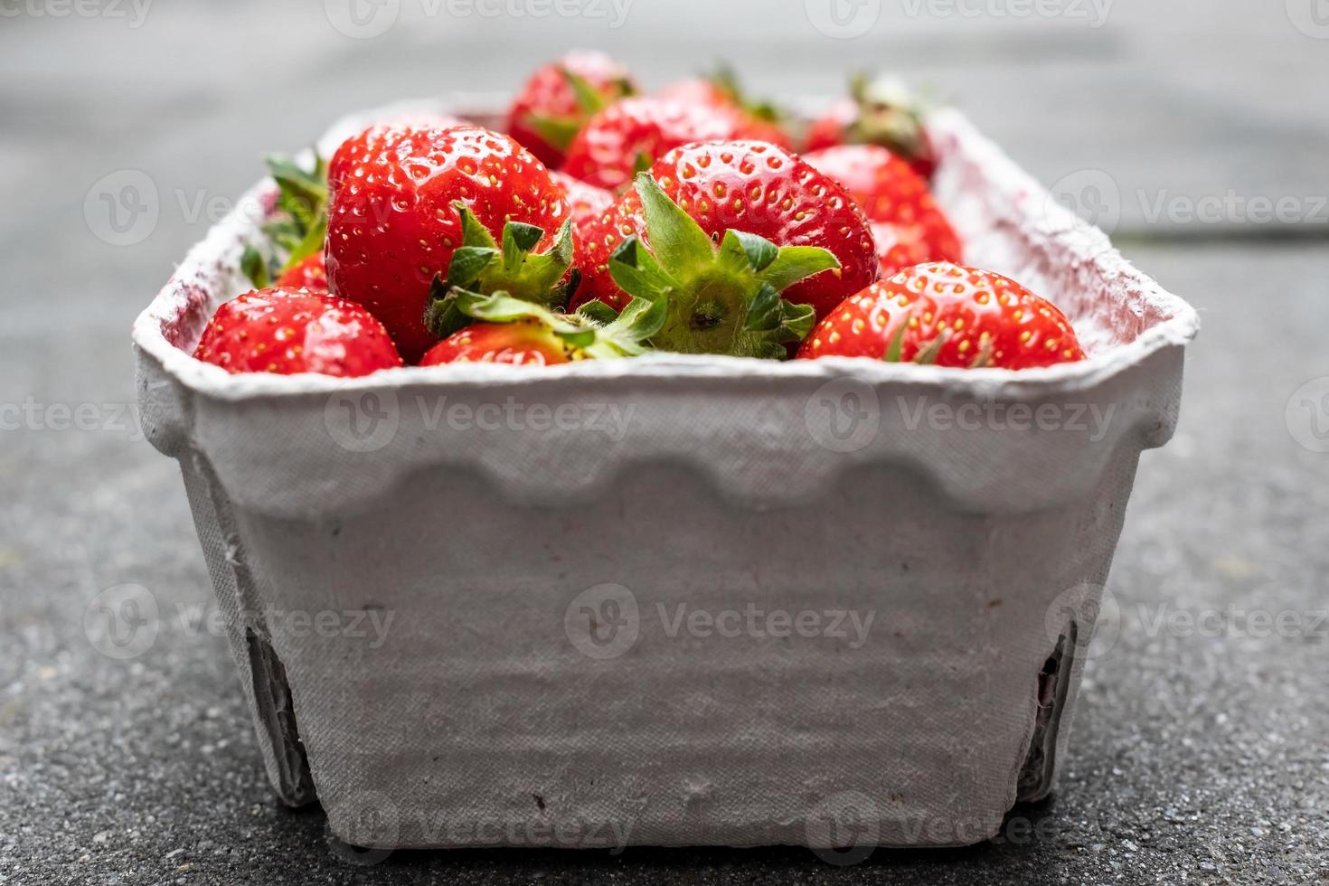 Delicious fragrant strawberries in a paper container, on the table. Red ripe berry is ready to eat. photo