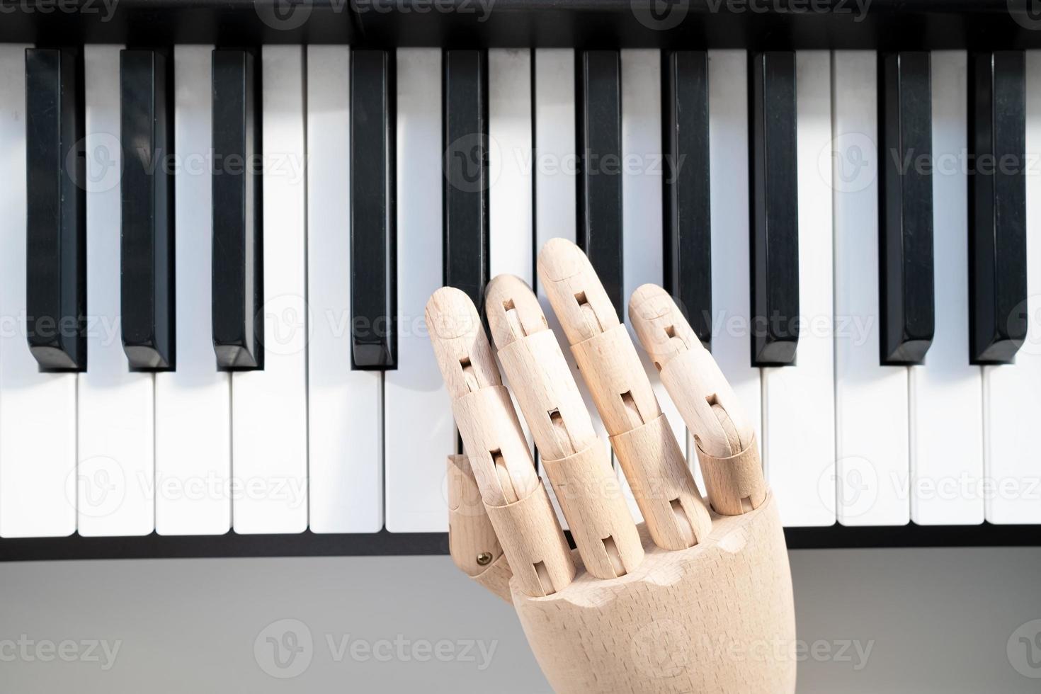 Wooden hand of a mannequin plays the piano, in natural light from the window. Top view. photo