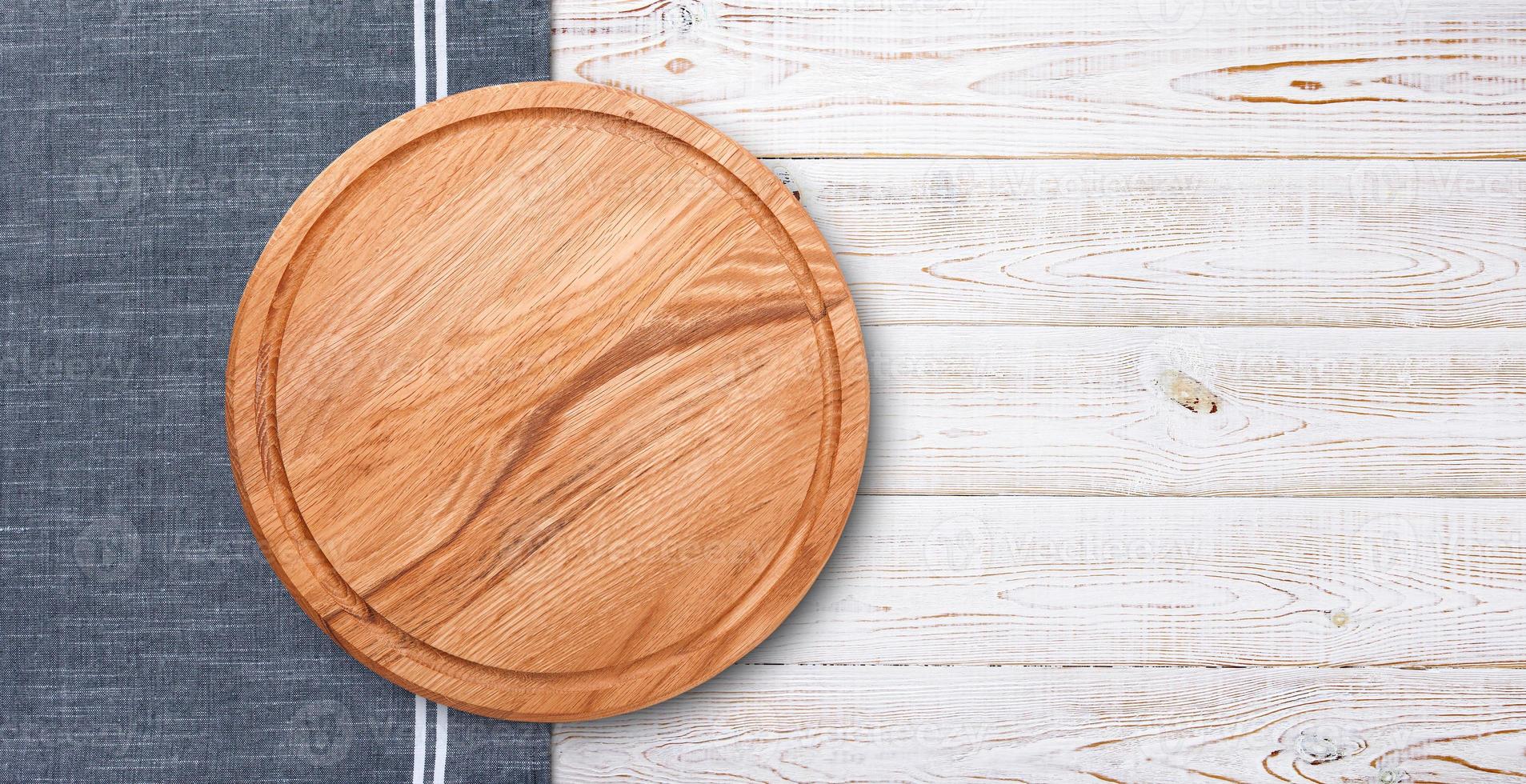 Pizza board with napkin on wooden table. Top view mockup photo