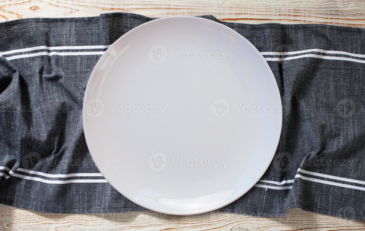 Empty white plate and napkin on light grey table, flat lay photo