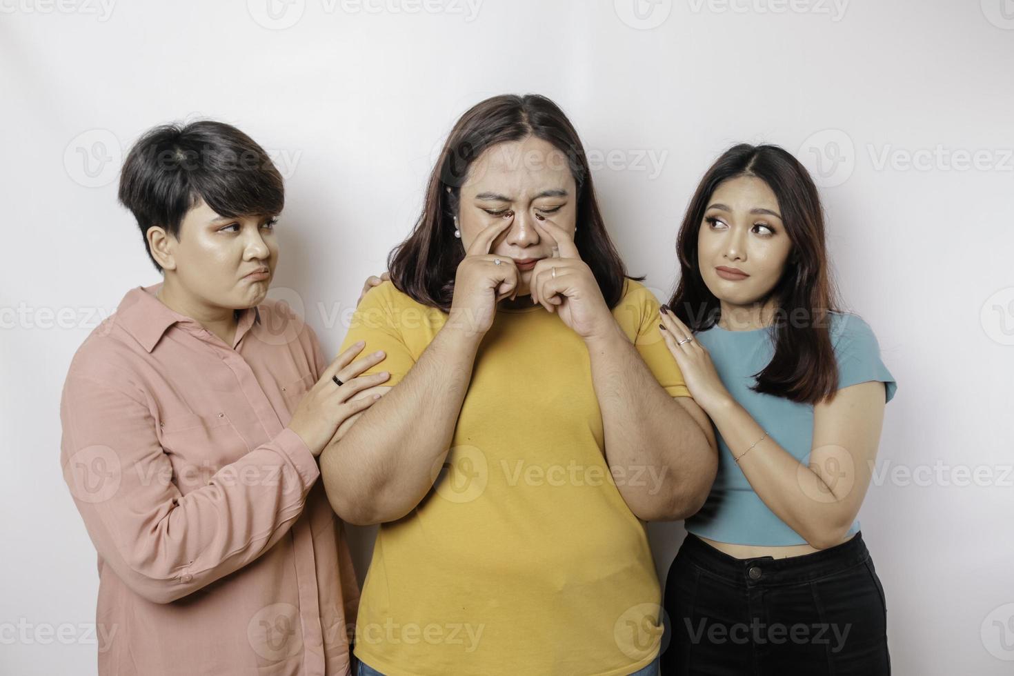 A portrait of three friends looking sad crying wiped her tears and hug each other, isolated white background photo