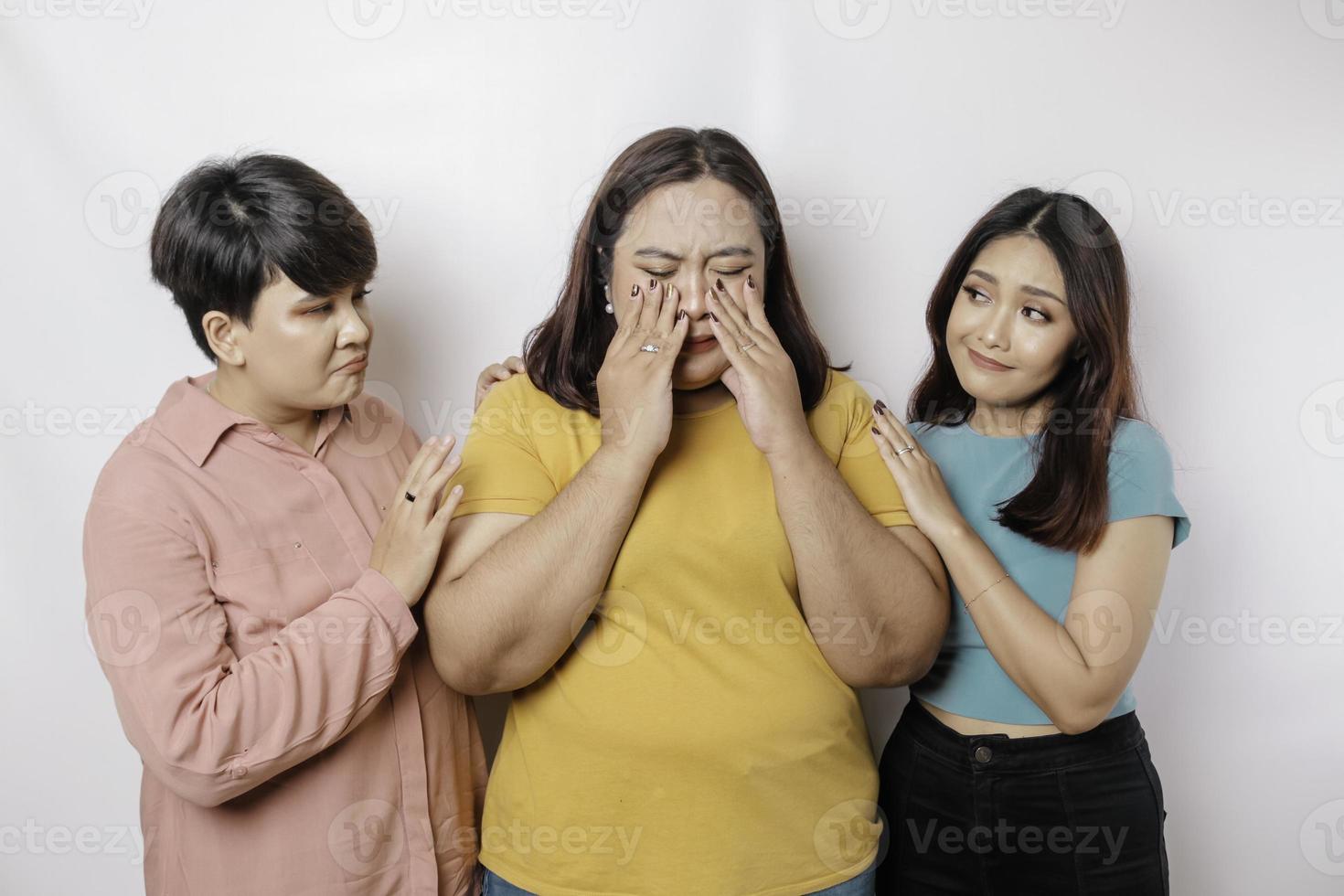 A portrait of three friends looking sad crying wiped her tears and hug each other, isolated white background photo