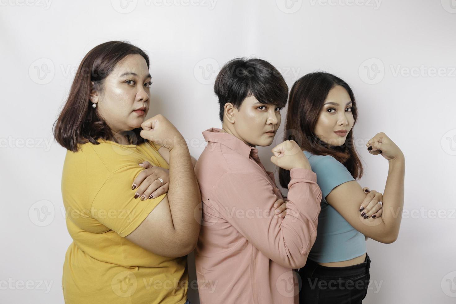 A portrait of three friends looks excited while showing strong gestures by lifting their arms and muscles and smiling proudly photo