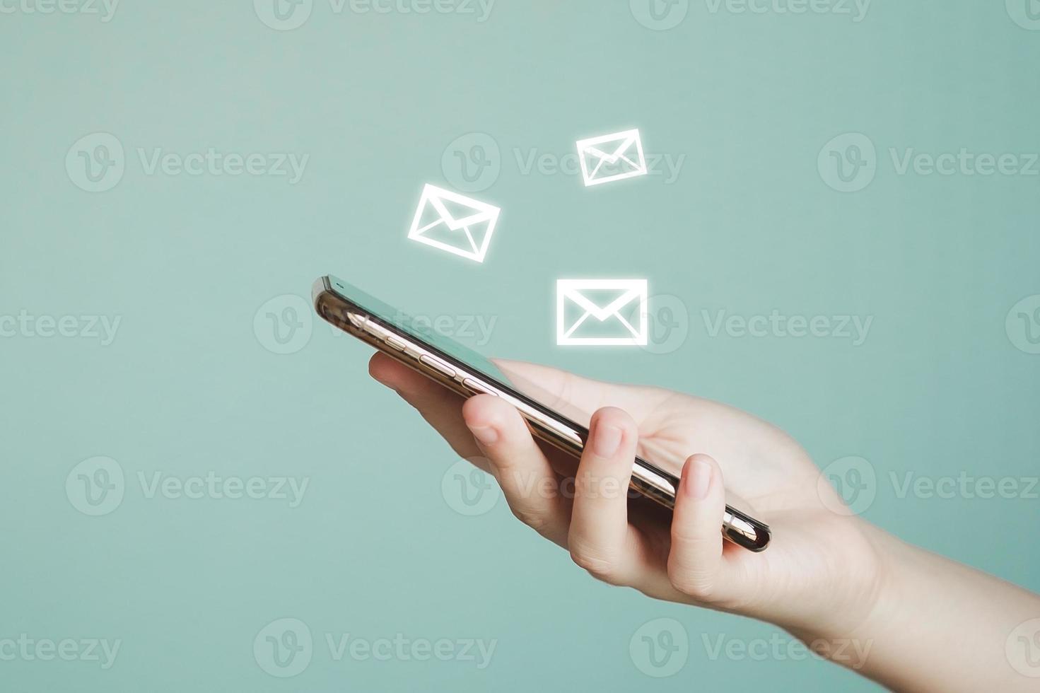 Hand holding smartphone and email icon to send or receive mail online on web. Communication and Technology concept. photo