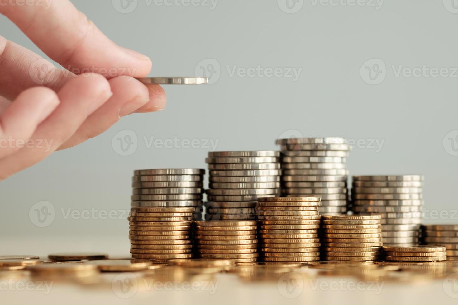 Hand hold a money coin for put on stack of coins. Financial and business, saving money, loan, tax, interest rate, plan for investment in the future concept. photo