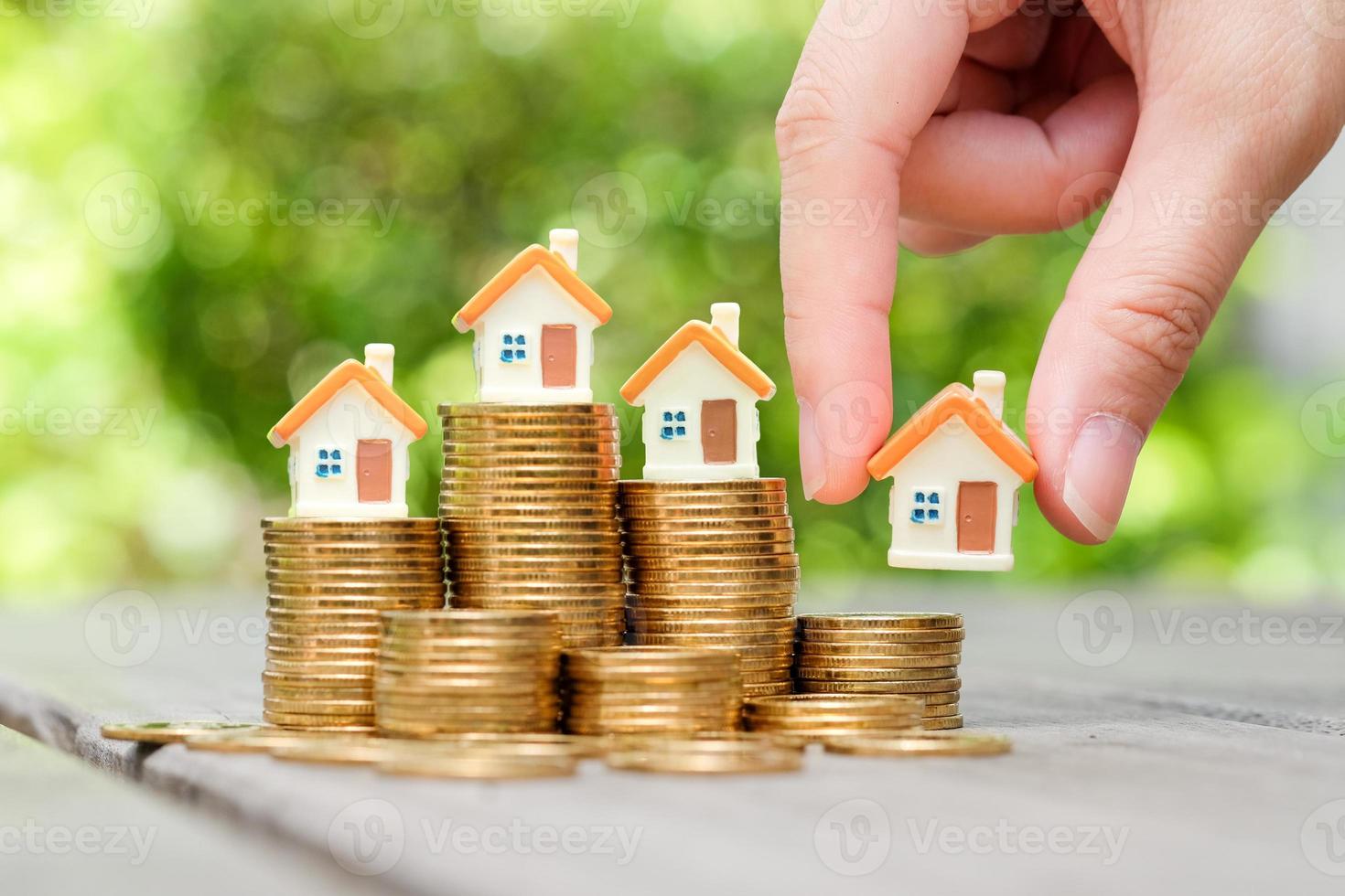 Hand choosing house on coins stack. House and property investment, Loan, Mortgage, Inflation, Sale and tax rise, Planning and Saving money for buy or rent home. Decision to choose best property. photo