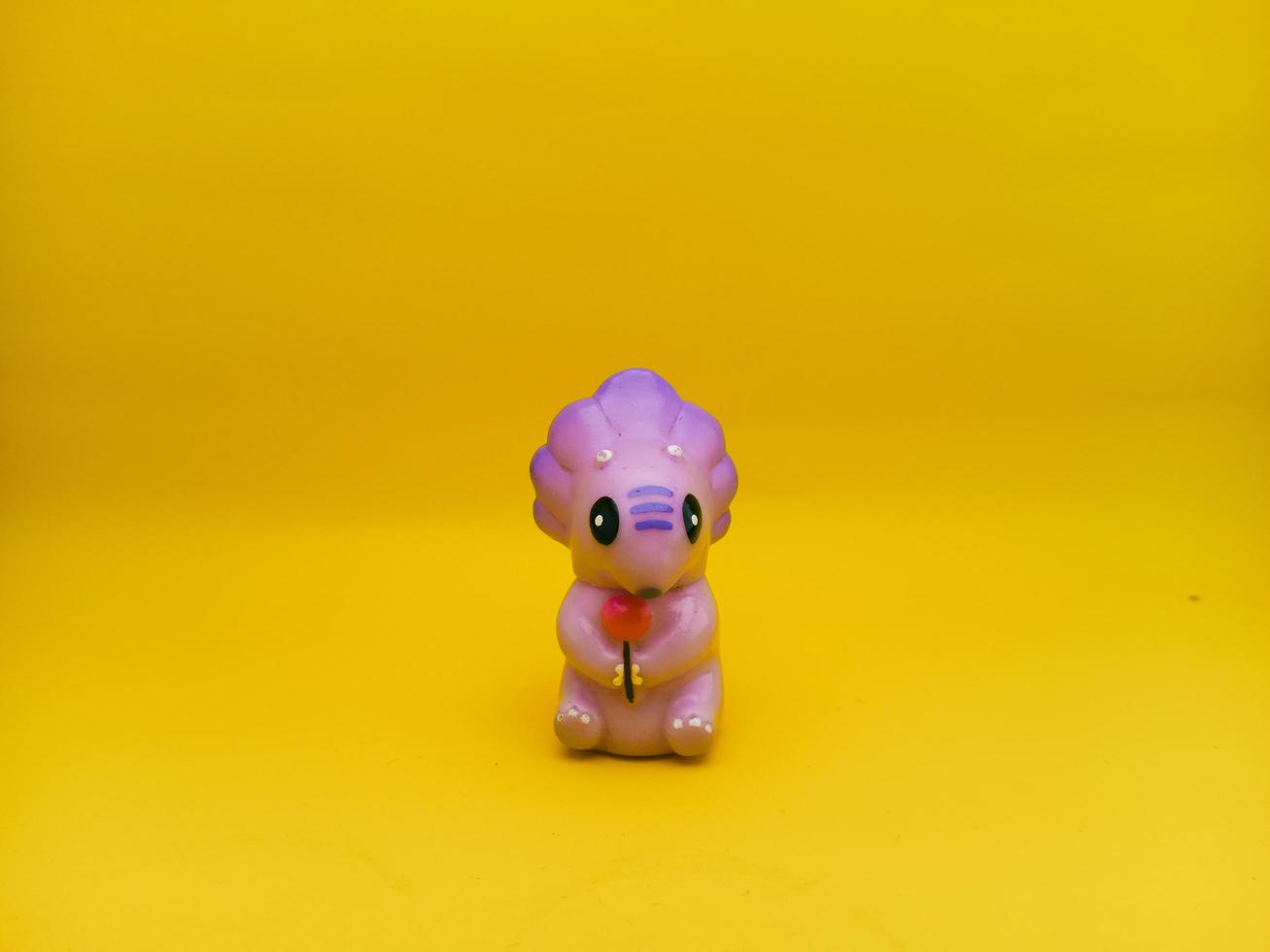 Purple dinosaur - shaped plastic toys with an isolated yellow background photo