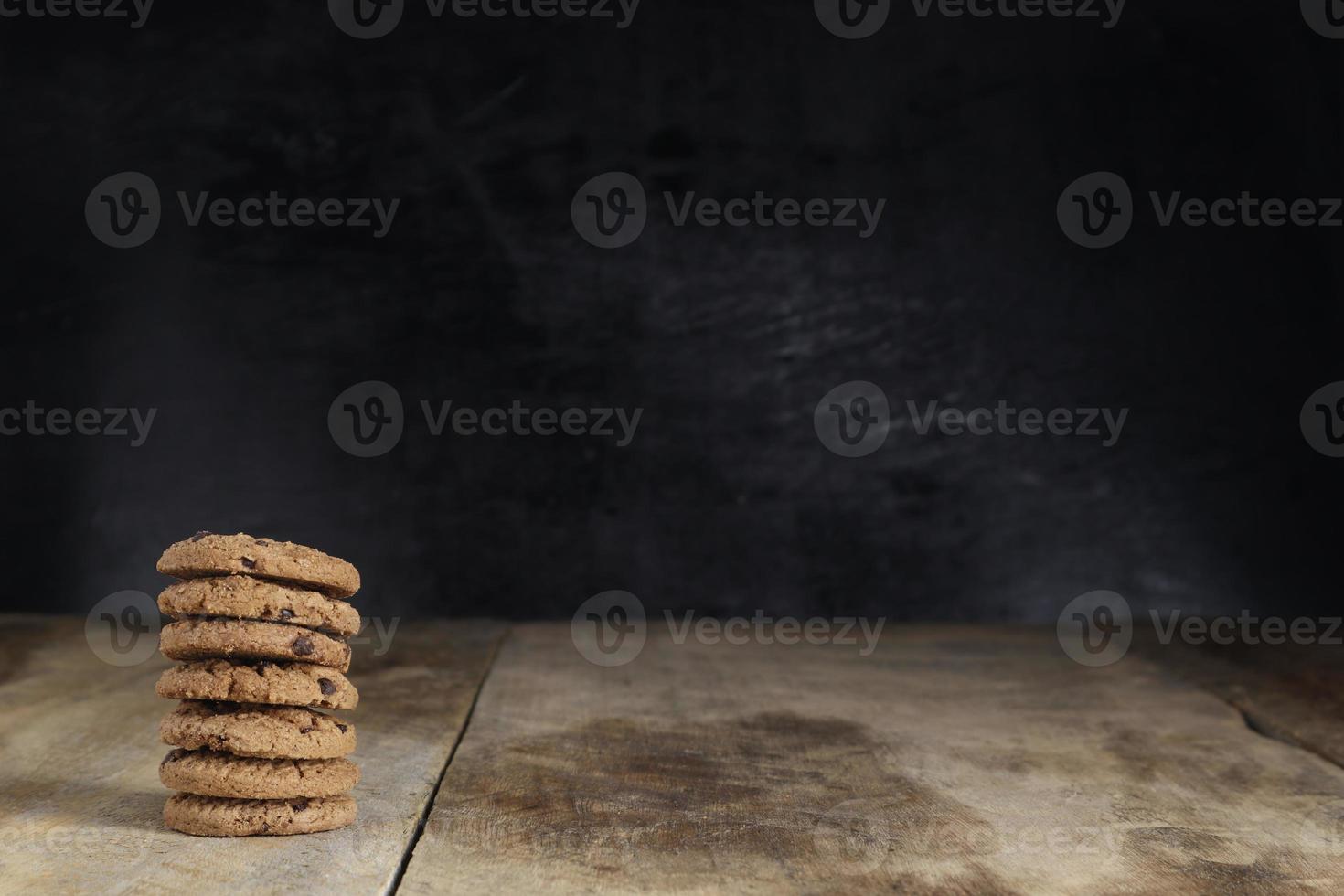 stack of chocolate cookies on wooden table on black background photo