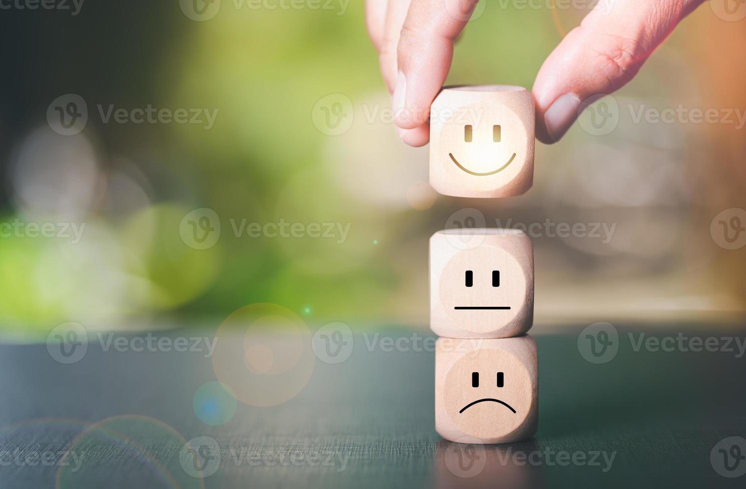 Human hand picking a wooden block with a smiley icon, photo